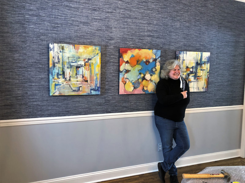 Martha with her 3 new abstract oil paintings by Sarah Baptist in her diningroom